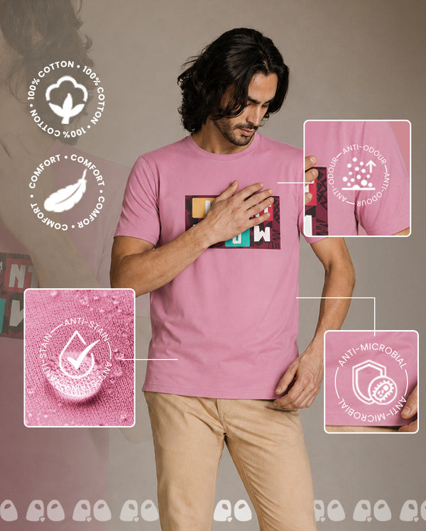 A man wearing a vandee pink short-sleeve t-shirt with a colorful geometric chest graphic, paired with beige pants.